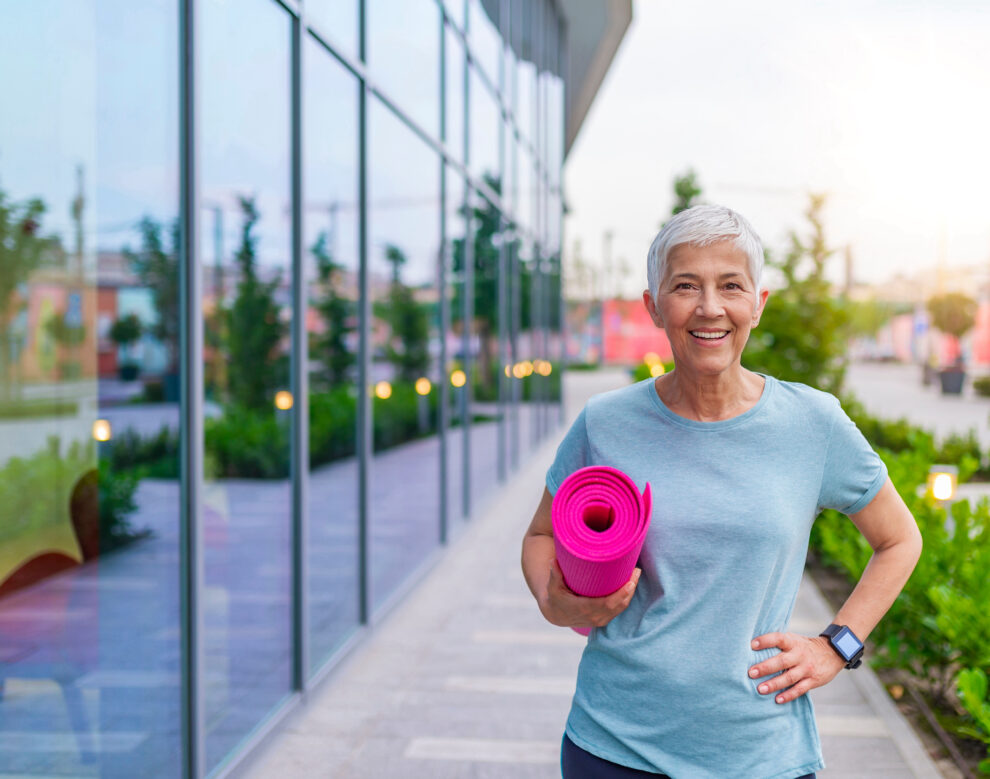 Portrait Of senior Woman Holding Exercise Mat